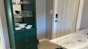 A kitchen with a green cabinet, a marble countertop, and a white door. - Divine Home Beach Retreat (Anavyssos)