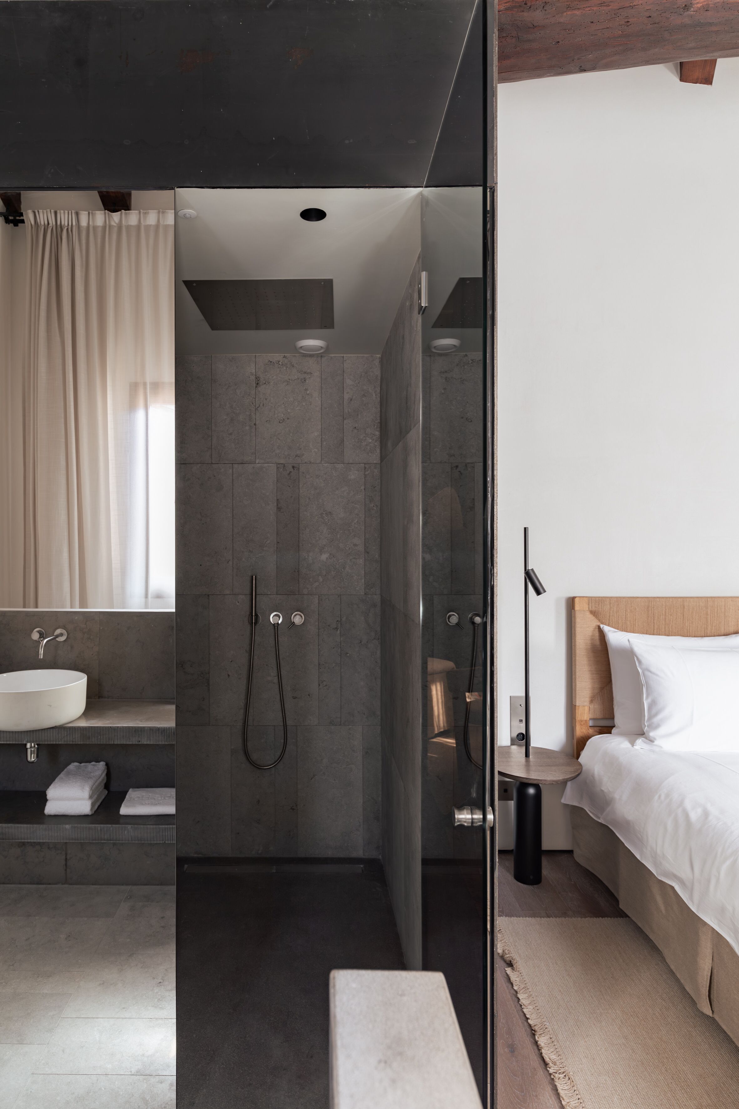 Un baño moderno con cabina de ducha de vidrio, lavamanos y mesita de noche.