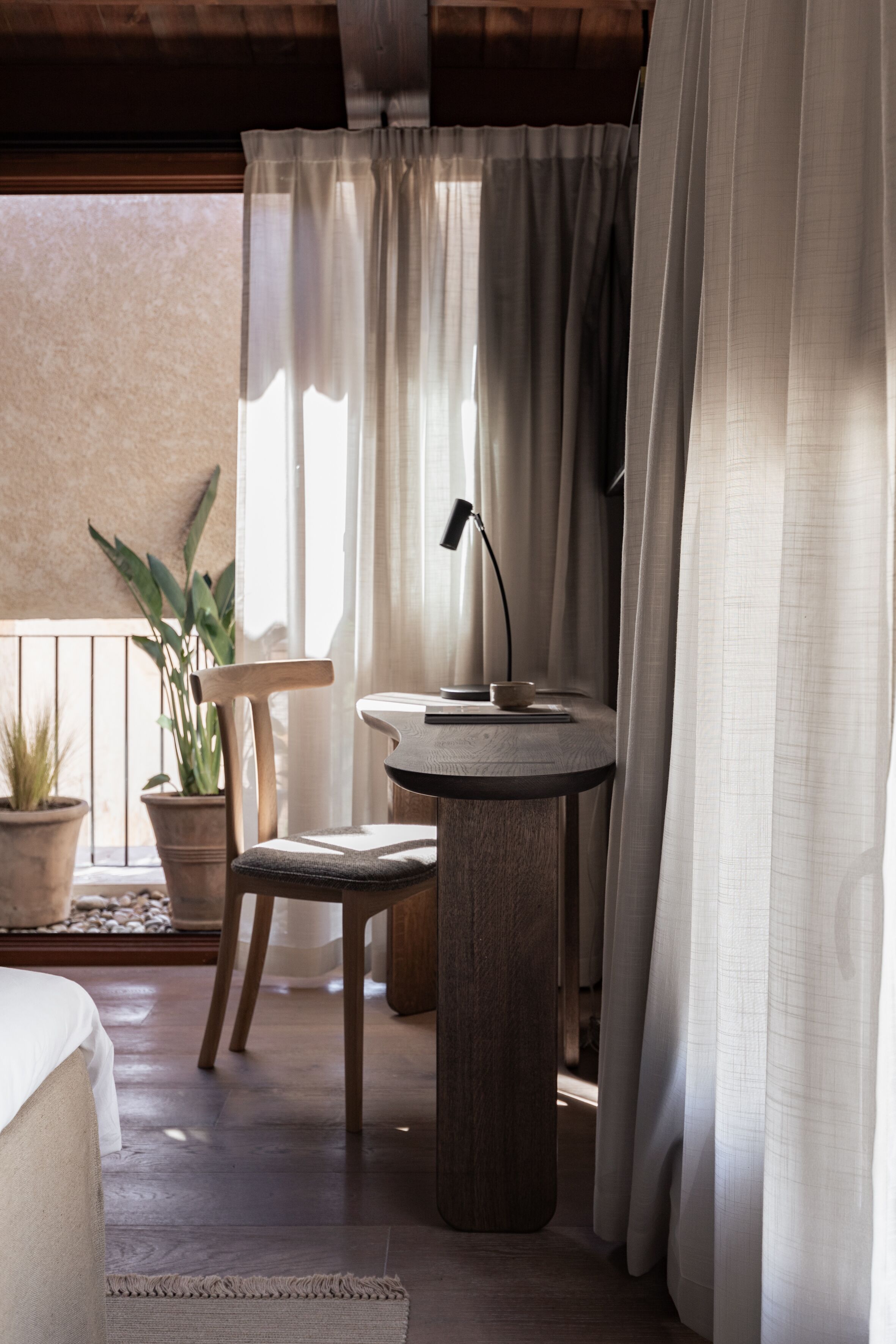 Una habitación acogedora con una mesa redonda de madera, una silla, una lámpara de escritorio y una planta en maceta.