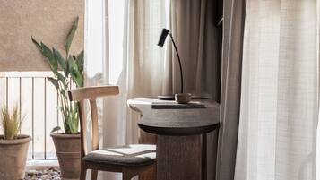 Een gezellige kamer met een ronde houten tafel, een stoel, een bureaulamp en een potplant.