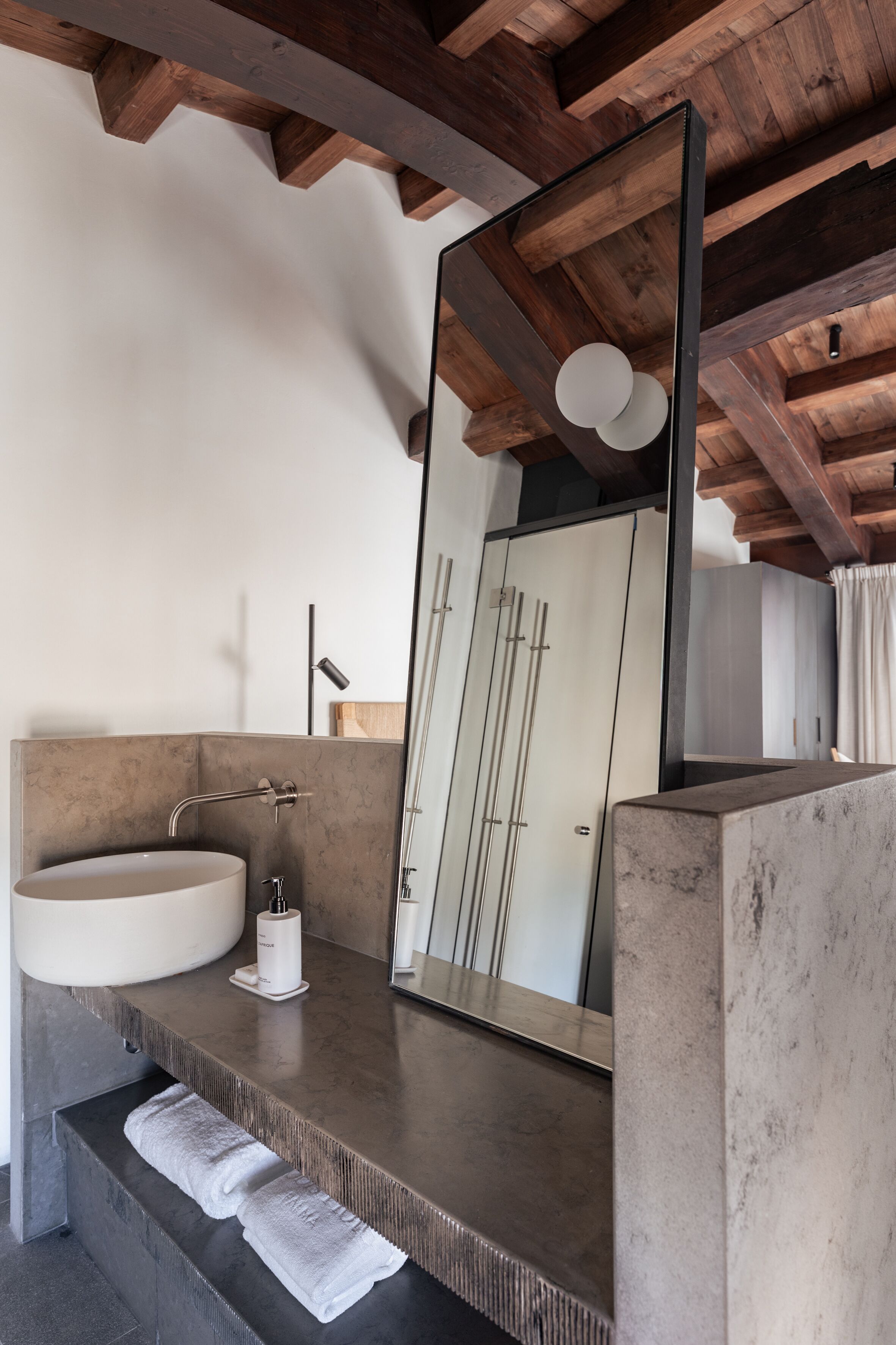 Un baño moderno con un espejo grande, un lavabo redondo y un perchero para toallas.