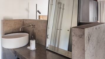 Un baño moderno con un espejo grande, un lavabo redondo y un perchero para toallas.