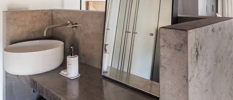 Un baño moderno con un espejo grande, un lavabo redondo y un perchero para toallas.