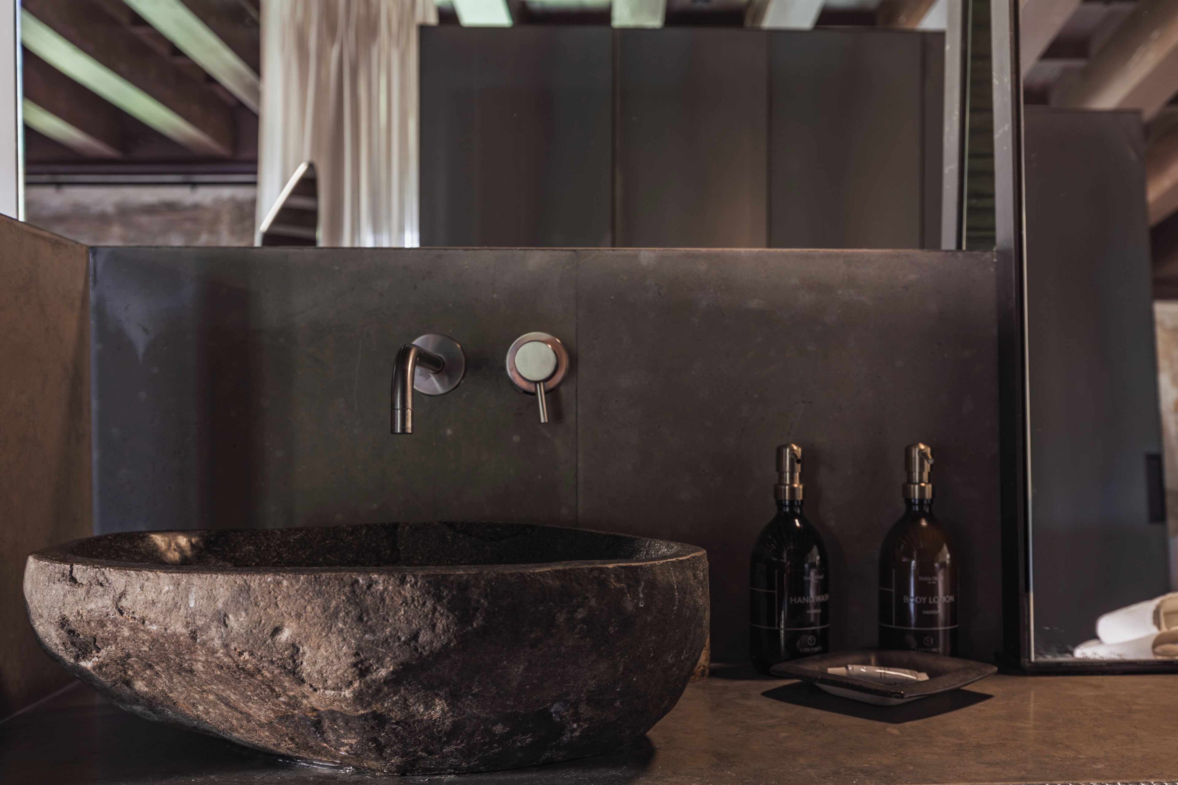Un baño moderno con un lavabo de piedra grande, dos grifos y dos botellas de jabón para manos.