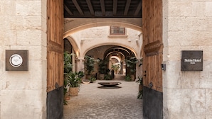 Un patio interior con suelo de piedra, puertas de madera y plantas en macetas.