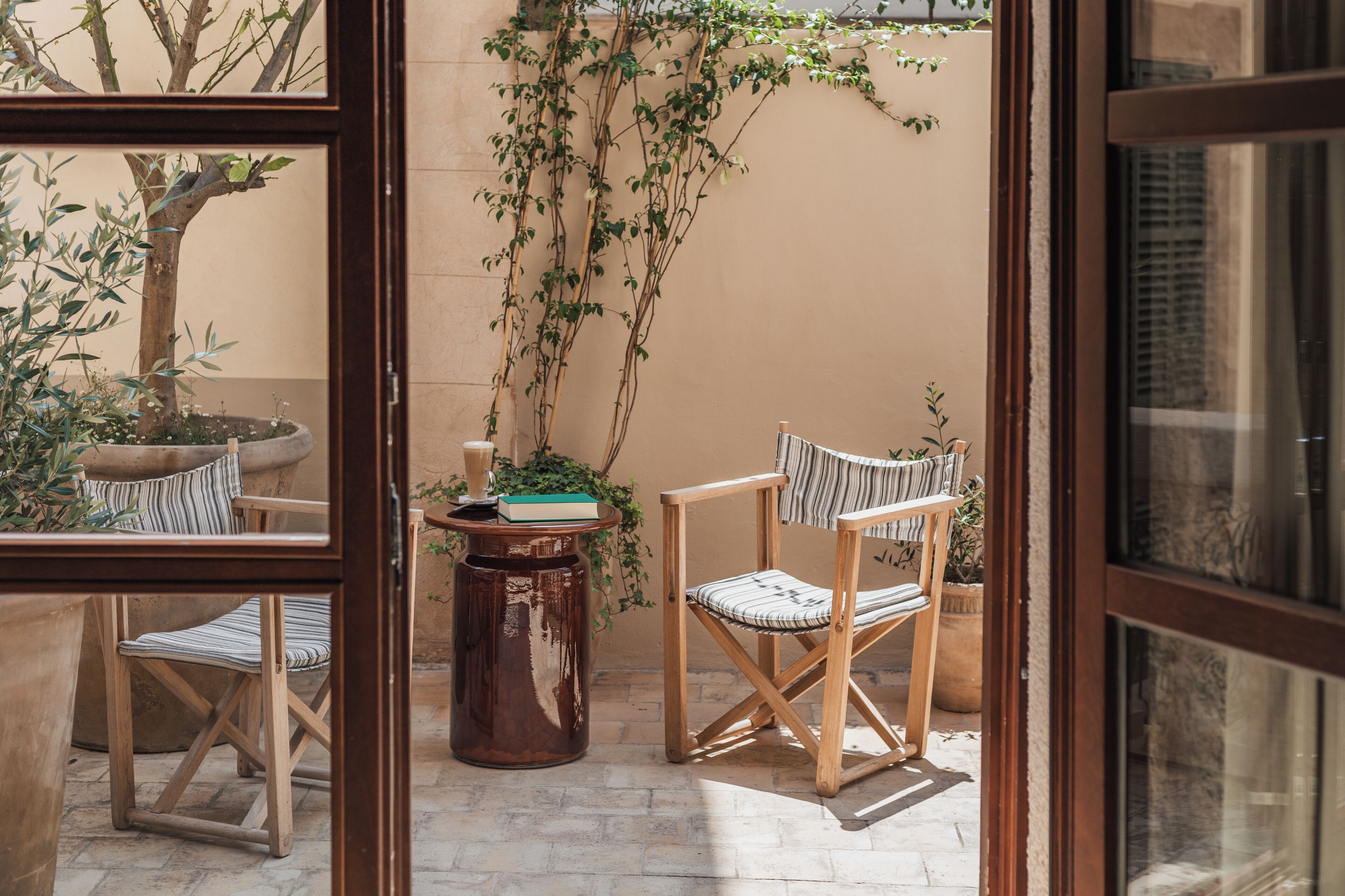 An outdoor seating area with two wooden chairs, a small round table, and a potted plant.