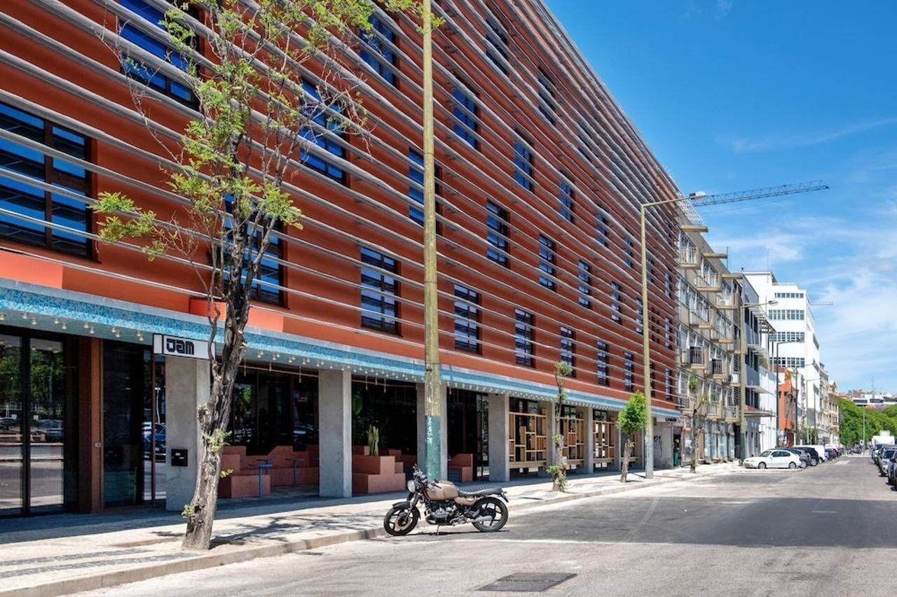 A modern building with a curved facade, large windows, and a tree in front.