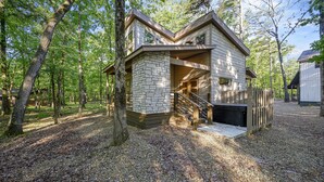 A cabin with a stone exterior, wooden deck, and a staircase leading to a covered porch. - Pets Welcome! King BR+Loft w/Hot Tub/Lg Patio! (Hochatown)