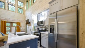 A modern kitchen with white cabinets, stainless steel appliances, and a blue island. - Pets Welcome! King BR+Loft w/Hot Tub/Lg Patio! (Hochatown)