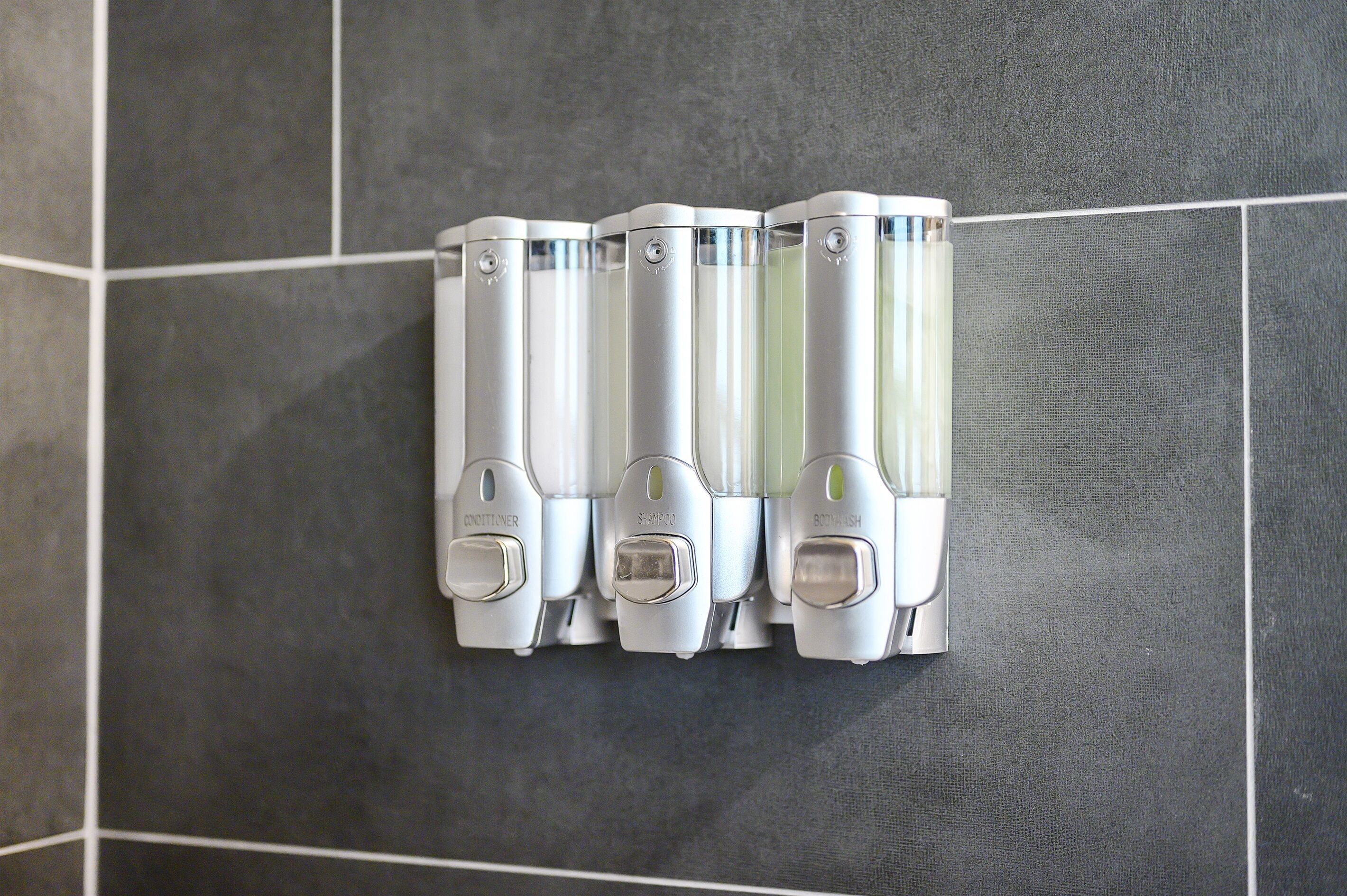 A wall-mounted hand dryer with a control panel, set against a tiled wall.