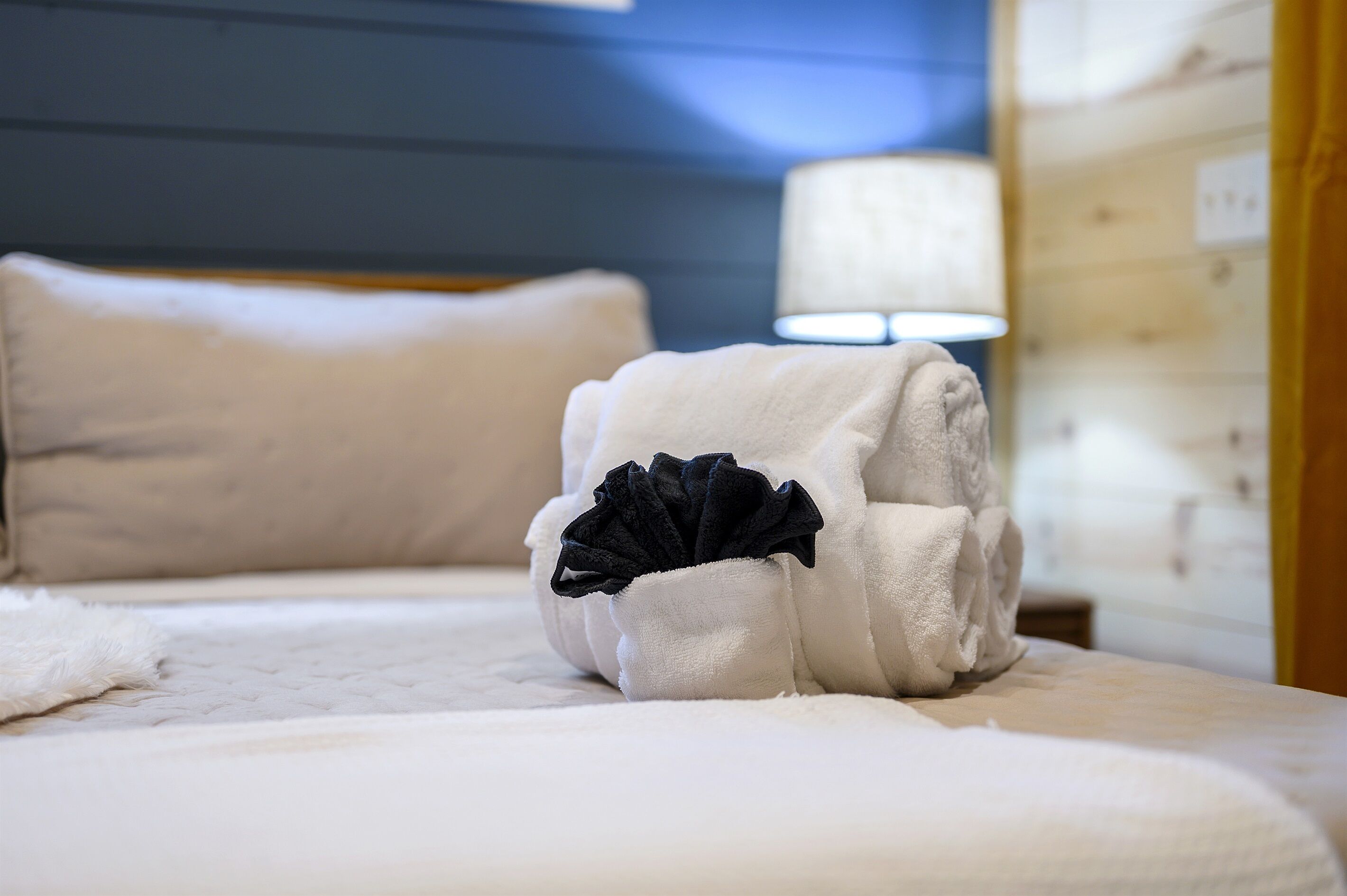 A neatly made bed with a white comforter and a decorative black flower arrangement on the pillows.