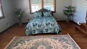 Ein Schlafzimmer mit einem Bett, einem Deckenventilator, zwei Fenstern und zwei Blumentöpfen.