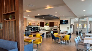 A modern restaurant with wooden accents, yellow and blue chairs, and a kitchen area visible in the background. - Comfort Inn & Suites Mountain Grove US-60 (Mountain Grove)