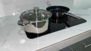 A kitchen with a stainless steel pot and pan on an induction cooktop.