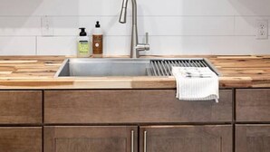 A kitchen with wooden cabinets, a stainless steel sink, and a black lantern on the shelf. - Downtown Spearfish Loft East (Spearfish)
