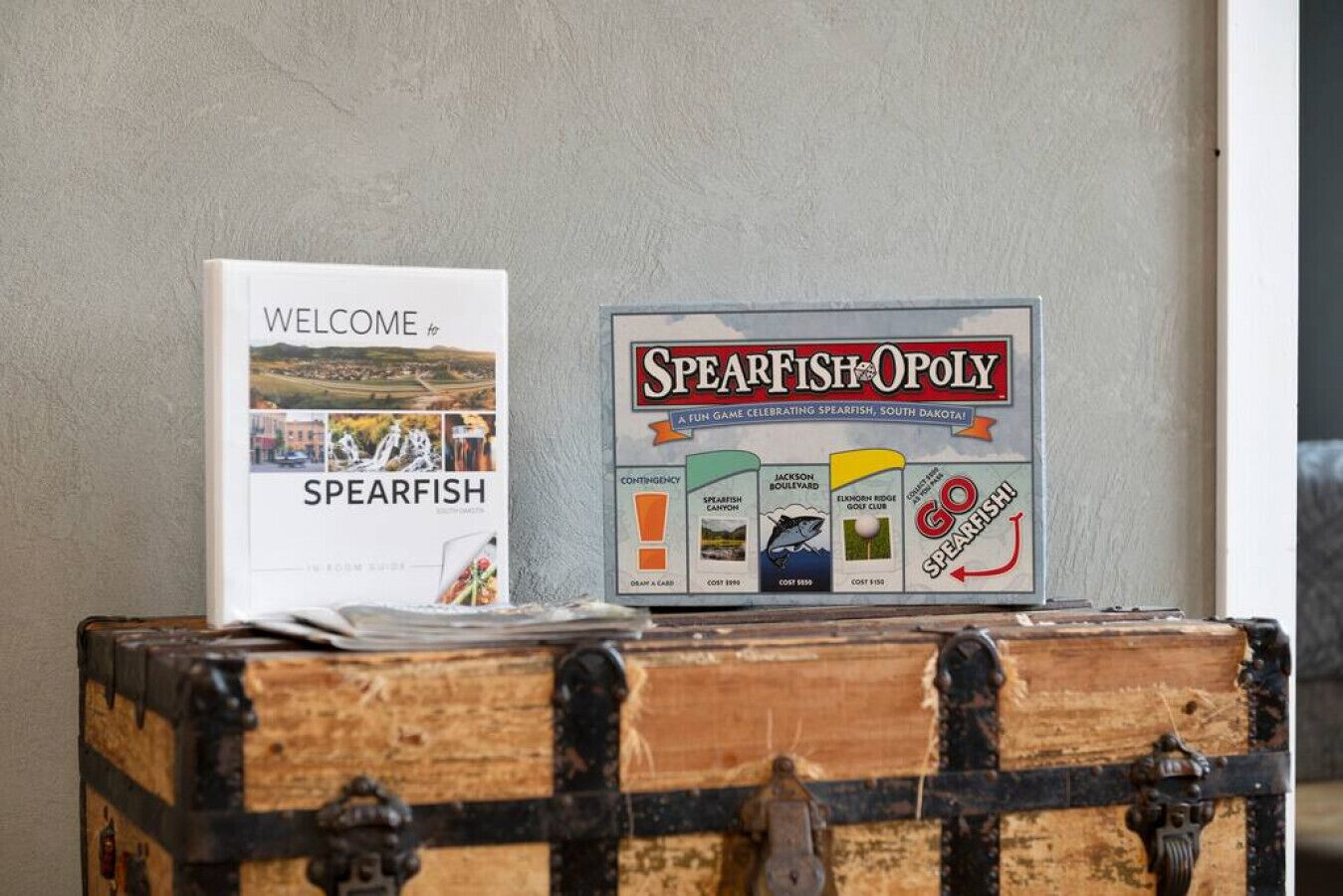 Un tablero de juego titulado 'Spearfish-Opology' y un folleto de bienvenida para Spearfish.