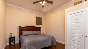 A bedroom with a wooden bed, a white door, and a ceiling fan. - Downtown Spearfish Loft West (Spearfish)