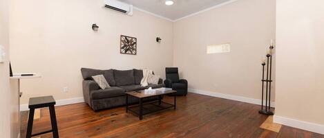 Una sala de estar con sofá, sillón, mesa de centro y lámpara de pie.