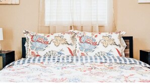 Een bed met kussens met bloemenprint en een geruit sprei.