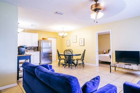 A compact living space with a dining area, a kitchenette, a TV, and a ceiling fan.