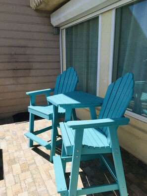 Une terrasse avec deux fauteuils Adirondack turquoise et une table assortie.