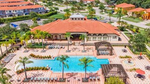 Resort com piscina ampla, palmeiras e área de varanda coberta.