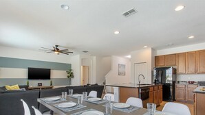 Um apartamento moderno com sala de jantar, cozinha, sala de estar e televisão.