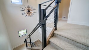 Un escalier moderne avec une rampe en métal et des marches recouvertes de moquette.