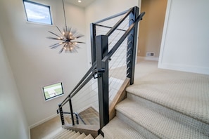 Una escalera moderna con barandilla de metal y peldaños alfombrados.