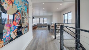 Un intérieur moderne comprenant un coin repas, un escalier et un grand tableau abstrait accroché au mur.