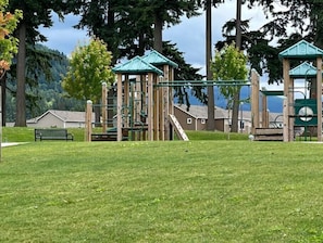 Explore the playground area surrounded by lush greenery and a bench for relaxation.