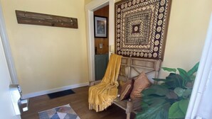 Une pièce chaleureuse avec un plancher en bois, un tapis à motifs, un lit avec une tête de lit, une tapisserie et une grande plante.