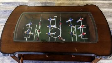 A tabletop foosball table with a glass top and wooden base.