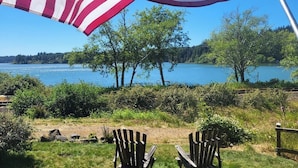 An American flag waving in front of a lake with two Adirondack chairs and a wooden fence. - Ticketmaster Chamber - Historic Lakefront Studio Cabin with Kayaking (oregon)