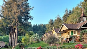 A row of wooden cabins with a stone wall and a green fence in front. - Ticketmaster Chamber - Historic Lakefront Studio Cabin with Kayaking (oregon)