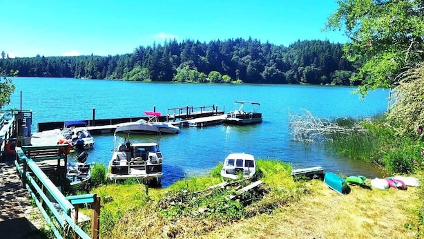 A lakeside dock with boats and a small docked vehicle. - Ticketmaster Chamber - Historic Lakefront Studio Cabin with Kayaking (oregon)