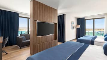 Une chambre d’hôtel avec une grande télévision, deux lits, un bureau et une chaise.