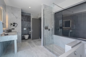 Een moderne badkamer met een douchecabine van glas, een toilet en een wastafel met een marmeren blad.