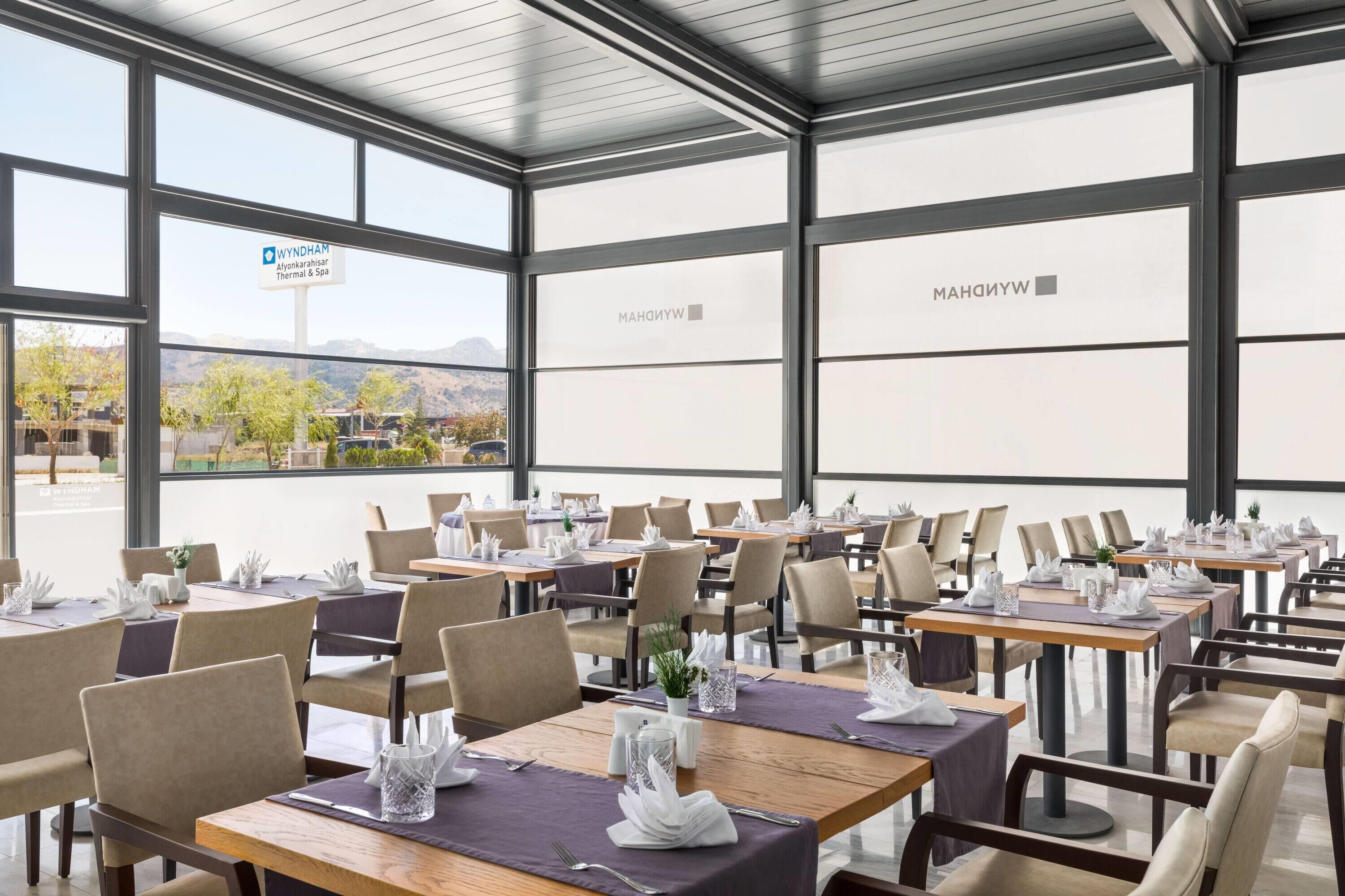A restaurant with multiple tables, each set with white napkins, cutlery, and glassware.