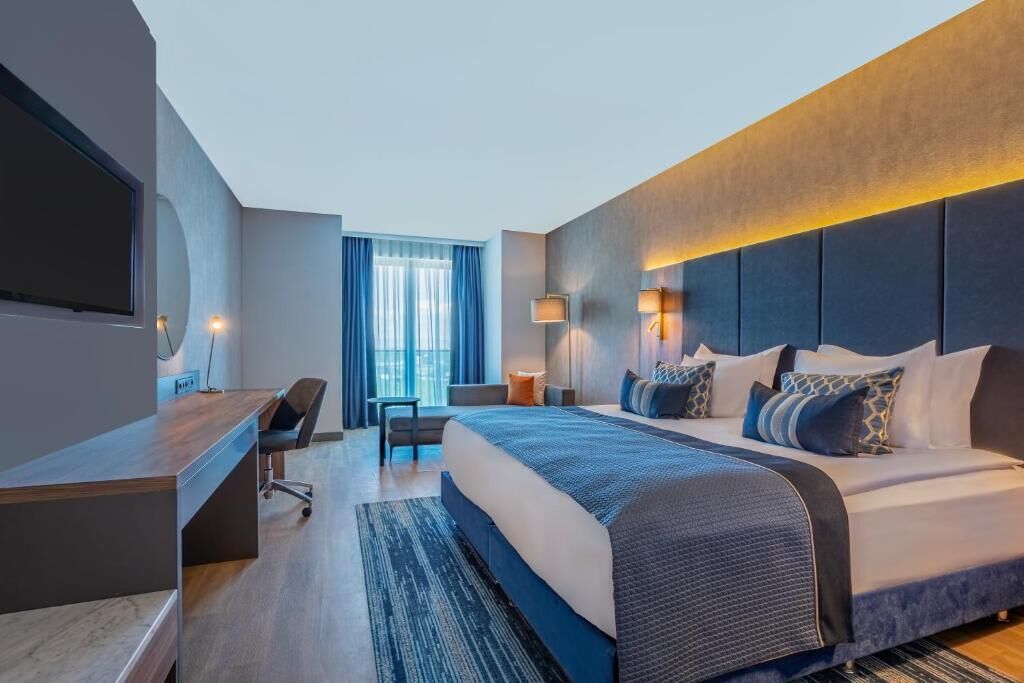 Une chambre d’hôtel moderne, dotée d’un grand lit, d’un bureau, d’une chaise et d’une télévision.