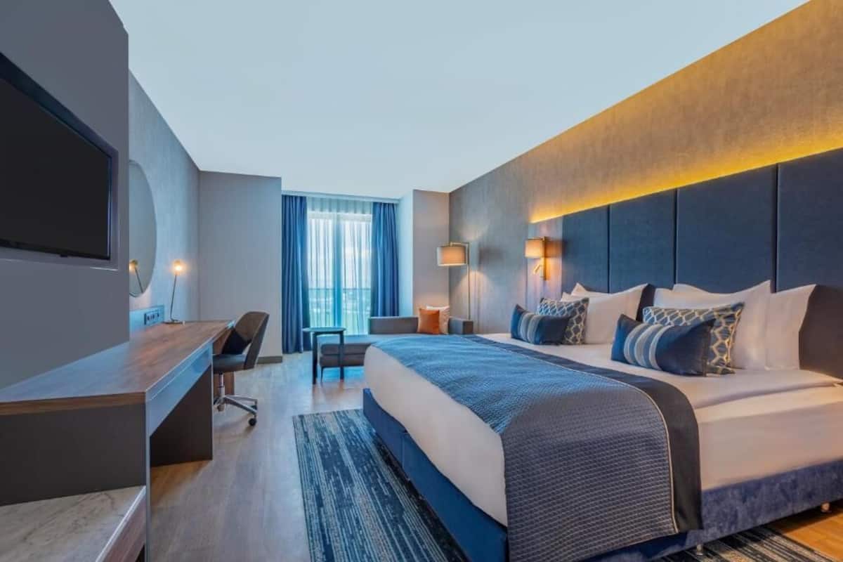 Een moderne hotelkamer met een groot bed, een bureau, een stoel en een televisie.