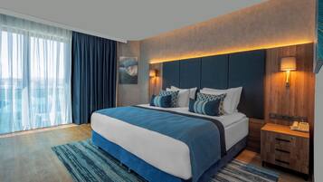 Una habitación de hotel moderna con una cama grande, un cabecero de madera y una mesita de noche con una lámpara.