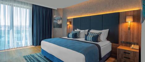 Una habitación de hotel moderna con una cama grande, un cabecero de madera y una mesita de noche con una lámpara.
