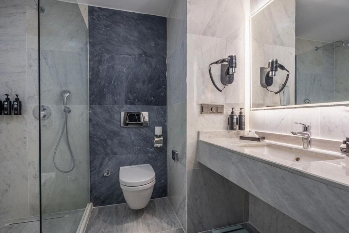 A modern bathroom with a glass-enclosed shower, a toilet, and a vanity with a mirror.