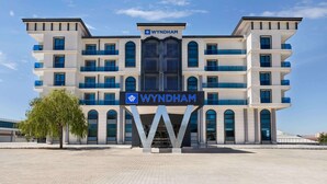 A modern Wyndham hotel with a prominent 'Wyndham' sign, multiple balconies, and a symmetrical facade.