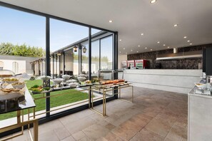 A modern kitchen with large windows, a dining area with outdoor seating, and a view of the surrounding landscape.