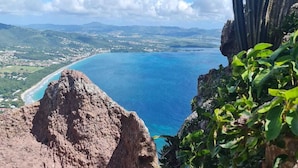 A coastal landscape with a rocky outcrop and a view of the sea and distant land. - T4 5 min from the beach (schoelcher)