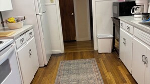 A kitchen with white cabinets, a refrigerator, a microwave, and a coffee maker.