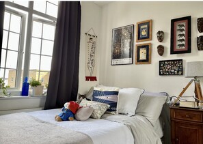 Cozy bedroom with a large bed, framed artwork, and a desk area.