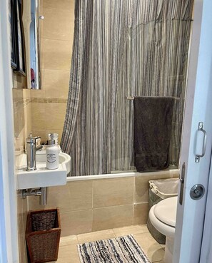 Bathroom features a bathtub, toilet, and sink with a soap dispenser.